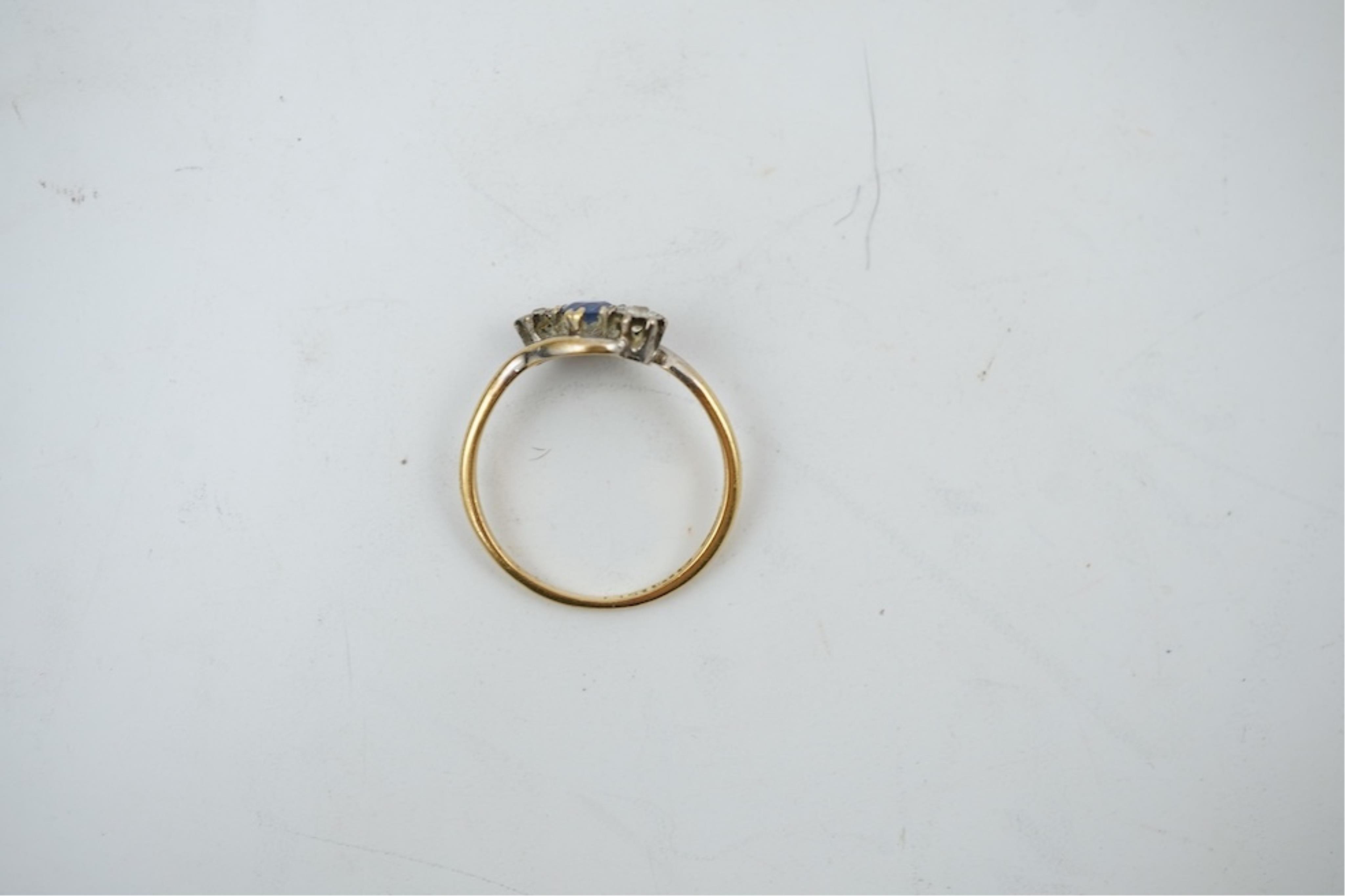 An early 20th century 18ct gold, sapphire and diamond set three stone crossover ring, size P/Q, gross weight 2.4 grams.
